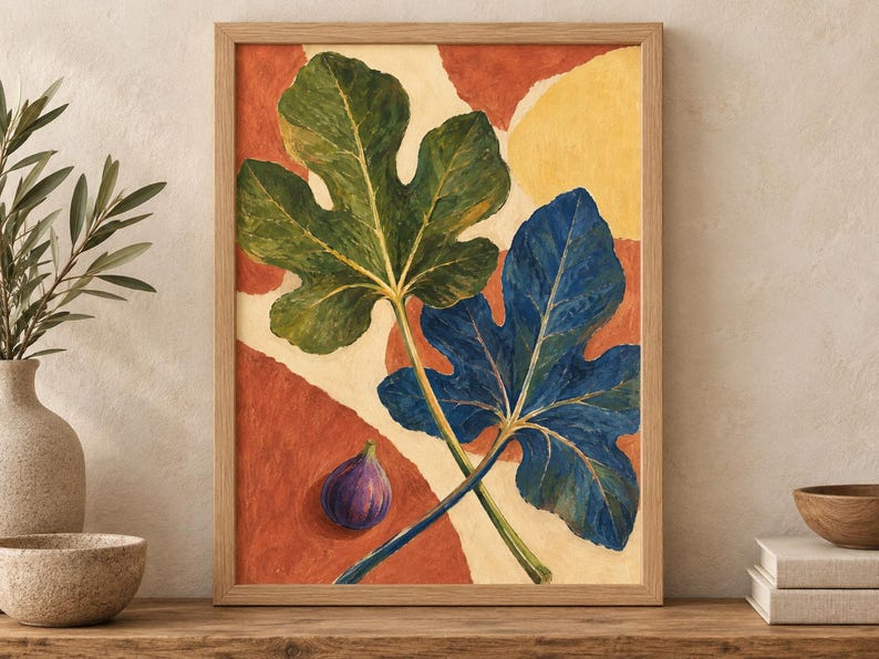 May include: A framed wall art print featuring a painting of two large fig leaves, one green and one deep blue, alongside a single purple fig. The background consists of abstract shapes in shades of terracotta orange and cream, set in a light wood frame.
