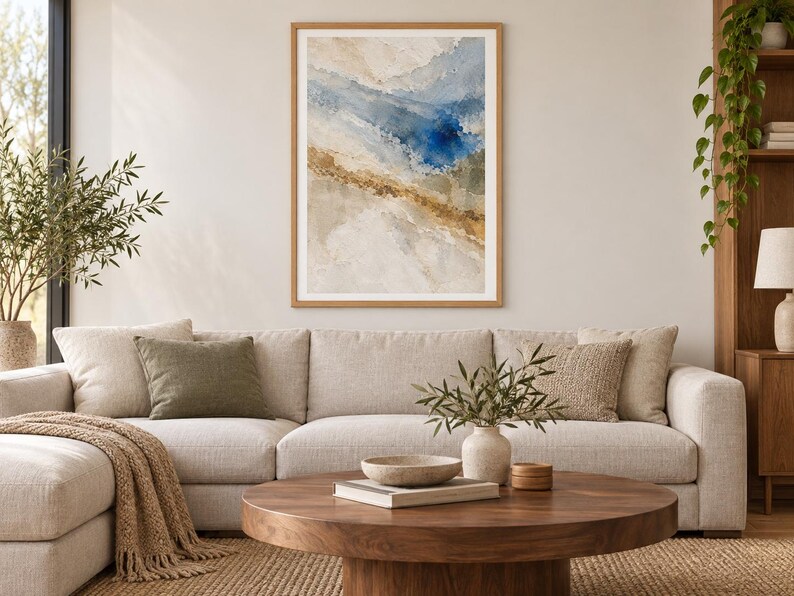 Puede incluir: Una impresi&oacute;n de arte abstracto enmarcada que presenta pinceladas texturizadas en tonos azul profundo, beige arena y blanco suave. La obra de arte se exhibe en un marco de madera clara, mostrando una composici&oacute;n fluida y en capas.