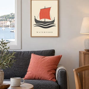 Pode incluir: Uma impress&atilde;o art&iacute;stica emoldurada com um navio viking preto estilizado com uma vela vermelha vibrante, navegando sobre ondas pretas num fundo creme. A palavra WATERFORD est&aacute; impressa em letras mai&uacute;sculas pretas na parte inferior.