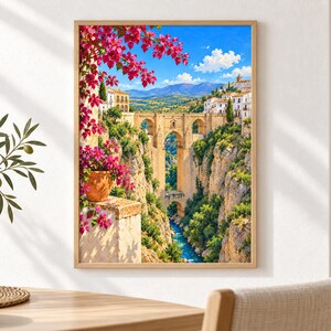 Pu&ograve; includere: Una stampa d'arte incorniciata che raffigura un paesaggio pittoresco con un ponte in pietra su una gola profonda. La scena presenta vivaci fiori di bouganville rosa in un vaso di terracotta, edifici bianchi su scogliere e un fiume blu.