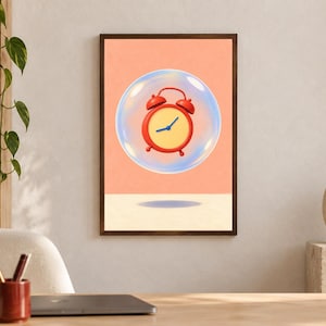 May include: A framed wall art print featuring a red analog alarm clock with a yellow face encased inside a transparent blue-tinted bubble. The background is a solid peach color with a cream-colored horizontal surface at the bottom.