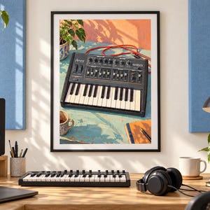 Op de afbeelding: Een ingelijste wandprint met een zwarte Arturia MiniBrute analoge synthesizer op een verweerd blauw oppervlak, vergezeld van een rode patchkabel, een keramische mok en een notitieboek met pen, alles verlicht door warm, natuurlijk zonlicht.