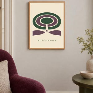 May include: A framed wall art print featuring a cream background with a central graphic design of concentric green and purple oval shapes. Below the shapes, a vertical line leads to a purple base, with the text ROSCOMMON printed in black.