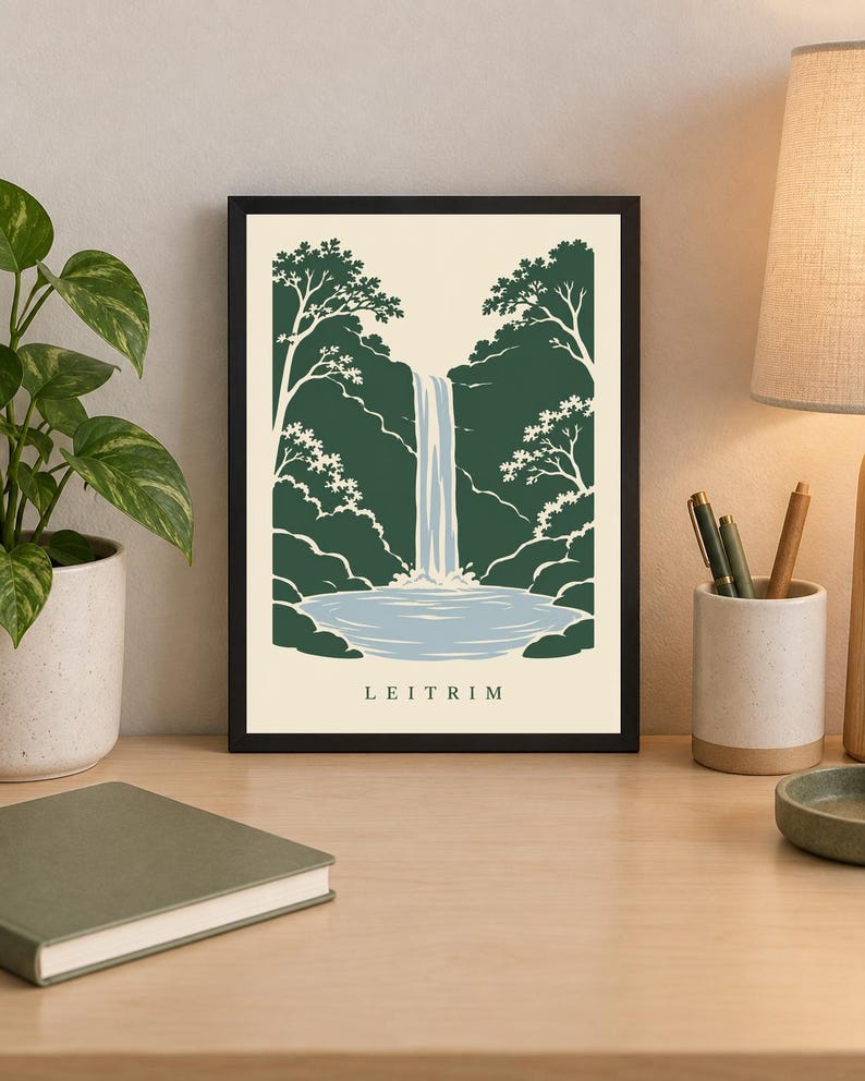 K&ouml;nnte beinhalten: Ein gerahmter Kunstdruck mit einer stilisierten Illustration eines Wasserfalls, der in ein Becken st&uuml;rzt, umgeben von dunkelgr&uuml;nen B&auml;umen und Blattwerk. Der Hintergrund ist cremefarben und das Wort LEITRIM ist unten mittig in Schwarz gedruckt.