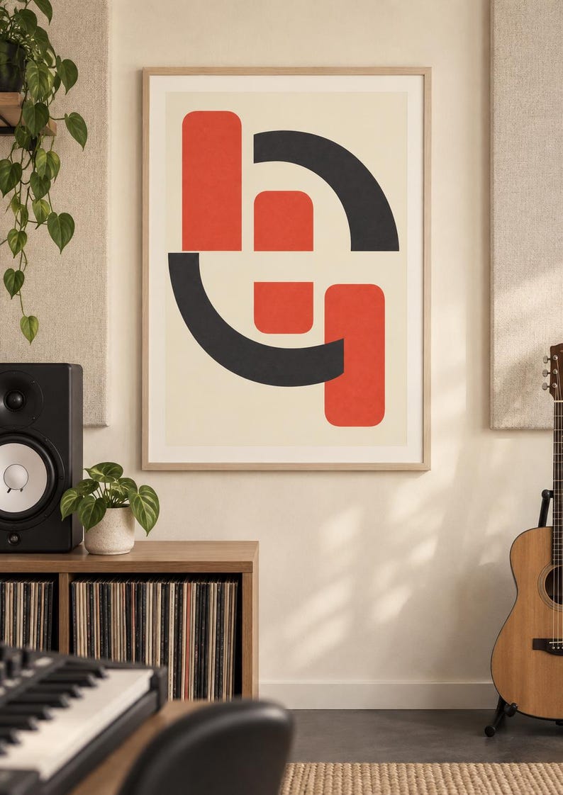 May include: A rectangular wall art print in a light wood frame featuring a graphic design of interlocking red and dark gray geometric shapes, including rounded rectangles and curved arcs, set against a solid off-white background.