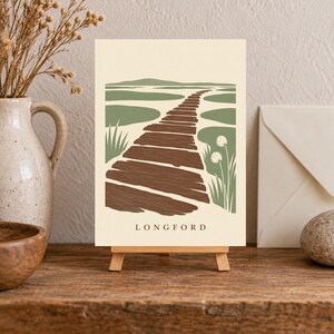 Puede incluir: Una l&aacute;mina rectangular sobre un peque&ntilde;o caballete de madera con una ilustraci&oacute;n paisaj&iacute;stica estilizada de un camino de madera marr&oacute;n que atraviesa un pantano verde sobre un fondo crema con el texto LONGFORD impreso en la parte inferior.