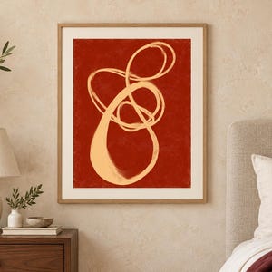 Pode incluir: Uma impress&atilde;o de arte de parede emoldurada com um fundo vermelho terracota profundo e uma linha &uacute;nica e cont&iacute;nua de cor creme claro que forma uma forma org&acirc;nica abstrata, em loop e rodopiante, centrada num passe-partout branco.