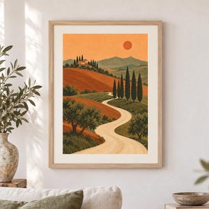 K&ouml;nnte beinhalten: Ein gerahmter Kunstdruck zeigt einen geschwungenen Feldweg durch eine h&uuml;gelige Landschaft mit Zypressen, Olivenb&auml;umen und einem Haus auf einem H&uuml;gel unter einem orangefarbenen Himmel mit einer runden Sonne. Das Bild zeigt warme Erdt&ouml;ne und Gr&uuml;n.