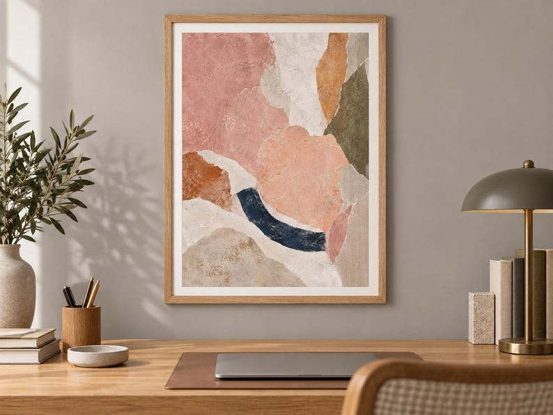 May include: A framed abstract wall art print featuring organic, layered shapes in muted tones of dusty pink, terracotta, olive green, white, and a deep navy blue curved accent, all enclosed within a light-toned wooden frame.