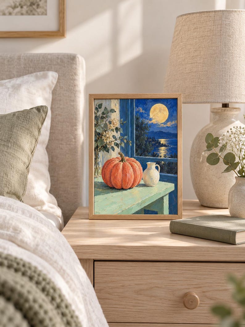 Pode incluir: Uma pintura retangular emoldurada retratando uma ab&oacute;bora laranja vibrante e um pequeno jarro branco sobre uma superf&iacute;cie verde-clara. A cena situa-se diante de uma janela com vista para um mar azul-escuro sob uma lua cheia brilhante.
