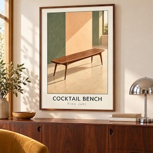 May include: A framed wall art print featuring a wooden bench in a room with green and beige walls. The text COCKTAIL BENCH and Finn Juhl is printed in black at the bottom. The image depicts a wooden bench with four tapered legs on a light floor.