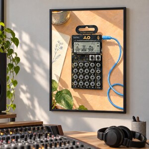 May include: A black Teenage Engineering PO-32 Tonic pocket operator synthesizer featuring a monochrome LCD screen with animated graphics, sixteen numbered buttons, and multiple control knobs, connected by a bright blue cable to a wall frame.