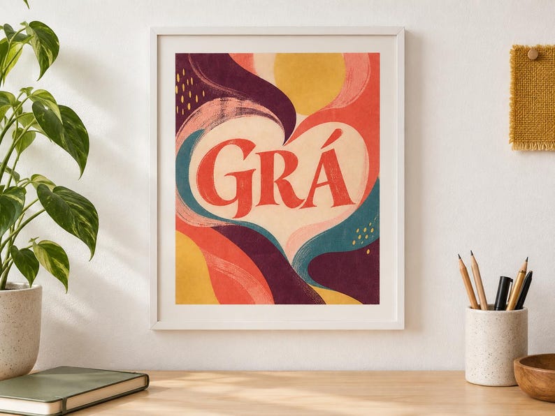May include: A framed wall art print featuring the word GR&Aacute; in large red serif letters centred within a cream-coloured heart shape. The background consists of abstract, flowing organic shapes in shades of deep purple, coral, yellow, and teal.
