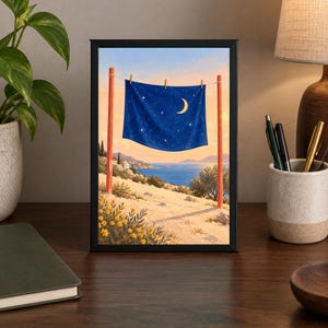 May include: A framed rectangular print featuring a dark blue fabric hanging on a clothesline between two red wooden posts. The fabric displays a crescent moon and stars against a coastal landscape with yellow flowers, hills, and a blue sea.