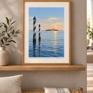 May include: A framed landscape print featuring two blue and white striped wooden mooring poles rising from calm blue water. In the distance, a small island with buildings is visible under a soft sunset sky with light clouds and a pale sun.