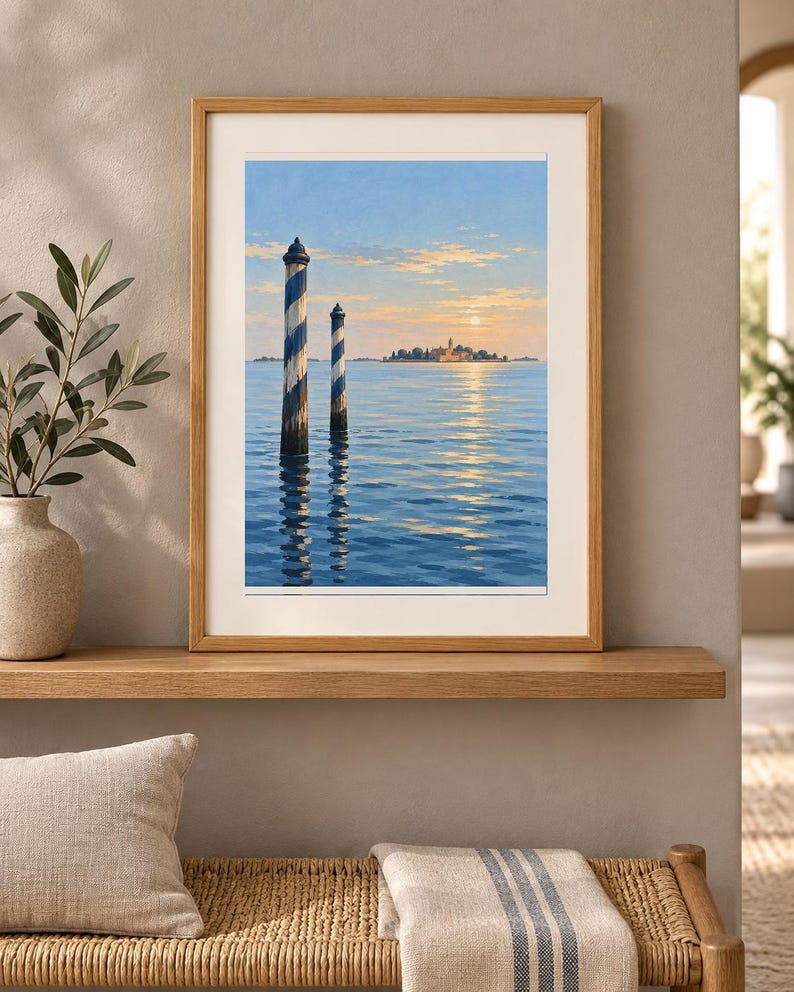 May include: A framed landscape print featuring two blue and white striped wooden mooring poles rising from calm blue water. In the distance, a small island with buildings is visible under a soft sunset sky with light clouds and a pale sun.