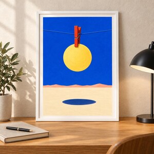Peut inclure: Une impression d'art encadr&eacute;e repr&eacute;sentant un paysage surr&eacute;aliste avec un cercle jaune vif suspendu par une pince &agrave; linge rouge sur une ligne fine contre un ciel bleu profond, au-dessus d'un sol d&eacute;sertique beige avec une ombre circulaire bleu fonc&eacute;.