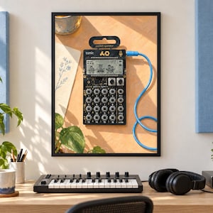 May include: A framed print featuring a black Teenage Engineering PO-32 Tonic pocket operator synthesizer with a digital screen, sixteen circular knobs, and a blue audio cable plugged into the side, displayed against a warm, light-colored background.