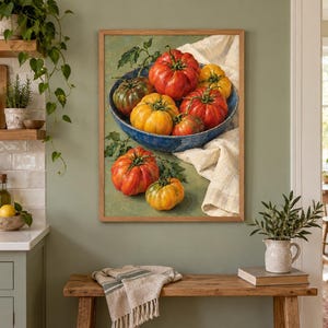 May include: A framed wall art print depicting a blue bowl filled with various heirloom tomatoes in shades of red, orange, and green, resting on a white cloth. Additional tomatoes are scattered on the surface below the bowl, all rendered in a painterly style.