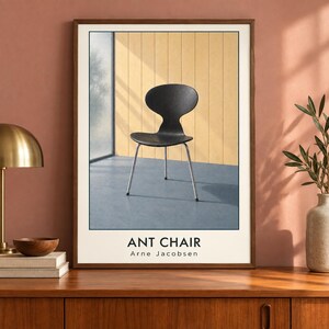 May include: A framed wall art print featuring a black Ant Chair by Arne Jacobsen. The chair has a curved seat and backrest with four thin metal legs. The print includes the text ANT CHAIR and Arne Jacobsen in black lettering at the bottom.