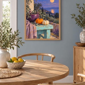 May include: A framed wall art print depicting a moonlit coastal landscape with a turquoise wooden table in the foreground. On the table sits a purple bowl, a bright orange pumpkin, a small white striped pumpkin, and a draped lavender fabric.