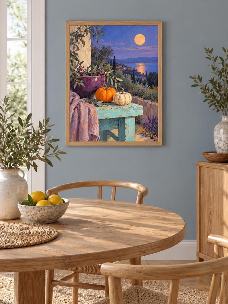 May include: A framed wall art print depicting a moonlit coastal landscape with a turquoise wooden table in the foreground. On the table sits a purple bowl, a bright orange pumpkin, a small white striped pumpkin, and a draped lavender fabric.