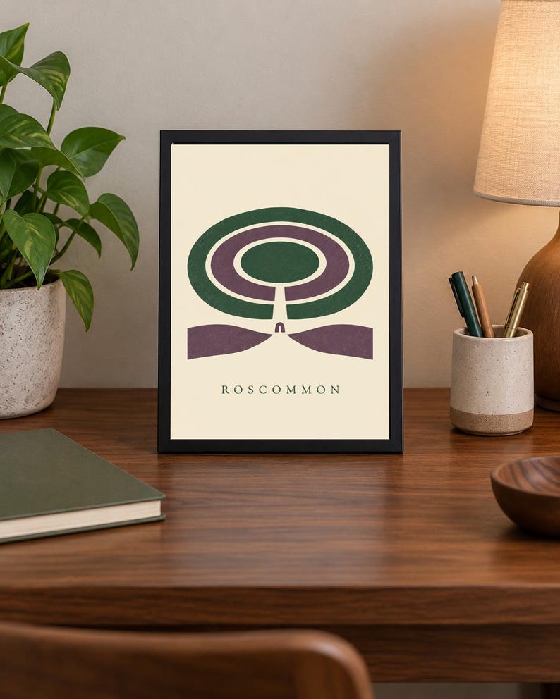 May include: A framed rectangular art print featuring a graphic illustration of a green and purple circular maze design on a cream background. The word ROSCOMMON is printed in black capital letters at the bottom centre of the artwork.