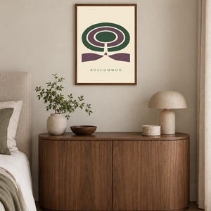 May include: A framed wall art print featuring a graphic design with concentric green and purple oval shapes above a purple base, with the text ROSCOMMON printed in black at the bottom, all set against a cream-coloured background.