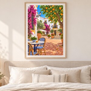 Puede incluir: Una impresi&oacute;n de arte mural enmarcada que representa un soleado patio mediterr&aacute;neo con una mesa redonda, dos sillas de rayas azules y blancas, flores de buganvilla rosa, un naranjo y una fuente de piedra bajo un cielo azul despejado.