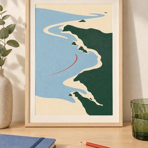 May include: A framed wall art print featuring a stylized coastal landscape with a light blue ocean, beige sandy shoreline, and dark green landmasses. A thin, curved red line is positioned in the water. The print is enclosed in a light wood frame.