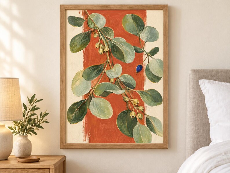 May include: A framed wall art print featuring a botanical illustration of a leafy branch with green foliage and small pale yellow buds against a vertical burnt orange stripe on a cream background, with one single small blue berry visible.