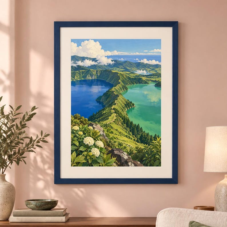 Puede incluir: Una impresi&oacute;n de paisaje enmarcada que muestra una vista elevada de dos lagos de cr&aacute;ter volc&aacute;nico adyacentes, uno azul profundo y otro turquesa, separados por una cresta verde. Flores de hortensia blancas florecen en primer plano bajo un cielo azul.