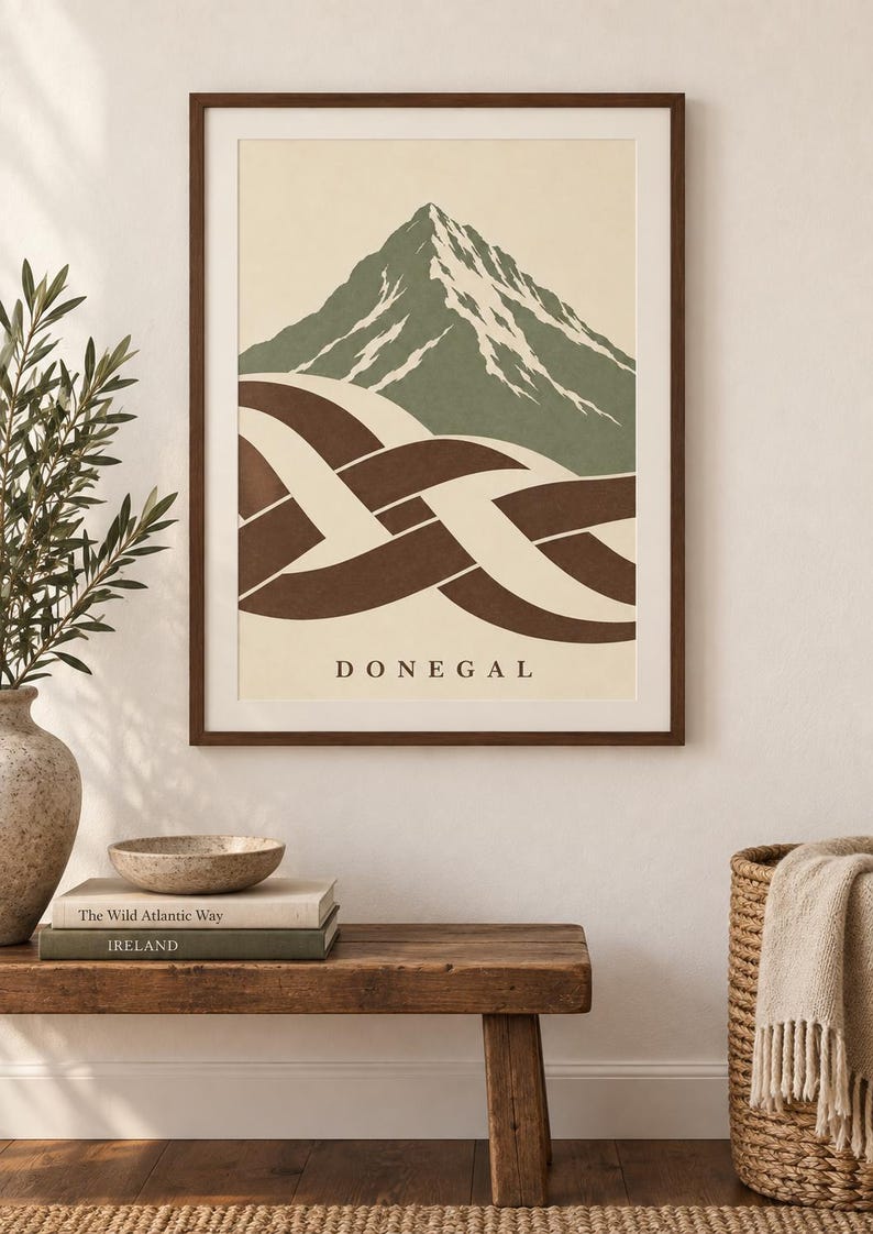 K&ouml;nnte beinhalten: Ein gerahmter Wandkunstdruck mit einem stilisierten Berggipfel in gedecktem Gr&uuml;n und Wei&szlig;, platziert &uuml;ber einem abstrakten braun-cremefarbenen keltischen Knotenmuster. Das Wort DONEGAL ist in schwarzen Gro&szlig;buchstaben auf dem cremefarbenen Hintergrund gedruckt.