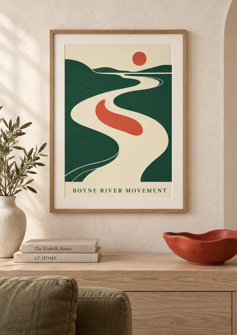 May include: A framed wall art print titled BOYNE RIVER MOVEMENT featuring a stylized landscape with a winding cream-colored river, dark green hills, a solid red sun, and a red abstract shape floating in the center of the river against a cream background.