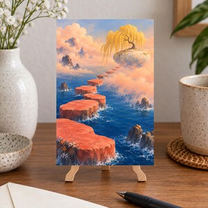 May include: A vertical art print on a wooden easel depicting a surreal landscape with a series of orange, flat-topped stone platforms leading across deep blue water toward a floating island topped with a golden willow tree under a cloudy sky.