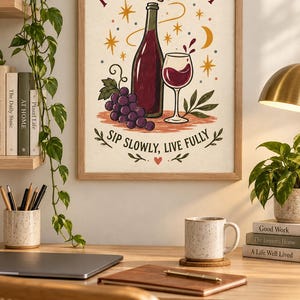 Puede incluir: Una l&aacute;mina de arte mural enmarcada que muestra una botella de vino, una copa de vino tinto y un racimo de uvas. El texto dice "POUR A LITTLE JOY" en la parte superior y "SIP SLOWLY, LIVE FULLY" en la inferior, con estrellas, luna y coraz&oacute;n.