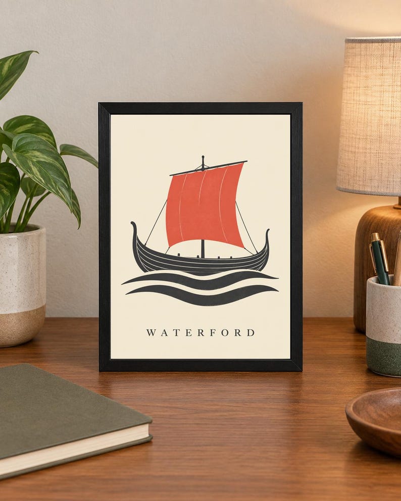 Pode incluir: Uma impress&atilde;o art&iacute;stica emoldurada apresentando um navio viking preto estilizado com uma grande vela vermelha, navegando sobre ondas pretas em um fundo creme. A palavra WATERFORD est&aacute; impressa em letras mai&uacute;sculas pretas na parte inferior.