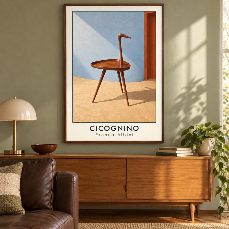 May include: A framed wall art print featuring a brown wooden Cicognino side table with a triangular top and three legs. The table is set against a light blue curved wall and a tan floor. The text CICOGNINO Franco Albini is printed below.