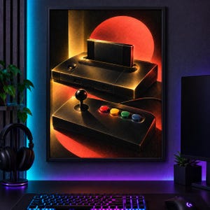 May include: A framed wall art print depicting a black retro video game console with an inserted cartridge and a matching controller featuring a black joystick and four colorful buttons, set against a background with a large glowing red circle.
