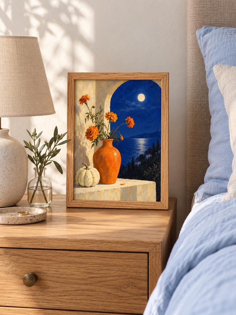 Puede incluir: Una l&aacute;mina enmarcada que representa un bodeg&oacute;n con un jarr&oacute;n naranja que contiene flores de cal&eacute;ndula naranjas y una peque&ntilde;a calabaza blanca sobre una repisa, frente a una vista nocturna de un mar iluminado por la luna.