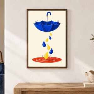 Pu&ograve; includere: Una stampa d'arte incorniciata raffigurante un ombrello blu sospeso in aria, che fa cadere gocce di pioggia blu e gialle in una pozzanghera rossa circolare su uno sfondo color crema. L'opera &egrave; racchiusa in una cornice di legno marrone scuro.