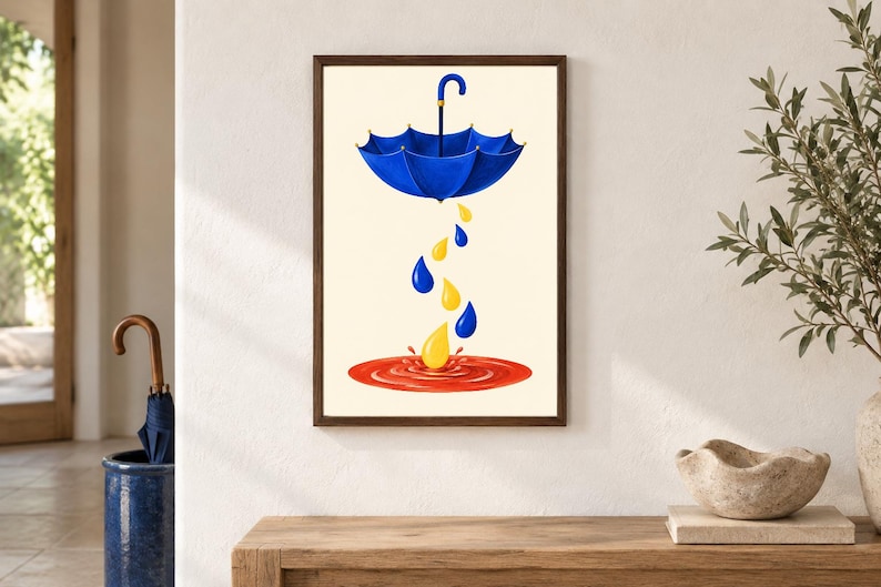 Pu&ograve; includere: Una stampa d'arte incorniciata raffigurante un ombrello blu sospeso in aria, che fa cadere gocce di pioggia blu e gialle in una pozzanghera rossa circolare su uno sfondo color crema. L'opera &egrave; racchiusa in una cornice di legno marrone scuro.