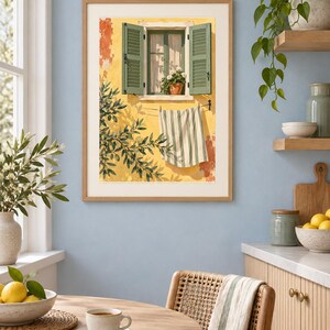 May include: A framed wall art print depicting a yellow Mediterranean building facade with open green shutters, a potted plant on the windowsill, and a striped towel hanging on a clothesline, with olive tree branches casting shadows on the wall.