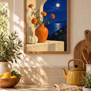 Puede incluir: Una l&aacute;mina de arte enmarcada que representa una escena nocturna con luna llena sobre un mar azul oscuro. En primer plano, un jarr&oacute;n de cer&aacute;mica naranja contiene flores de cal&eacute;ndula de color naranja brillante junto a una calabaza blanca.