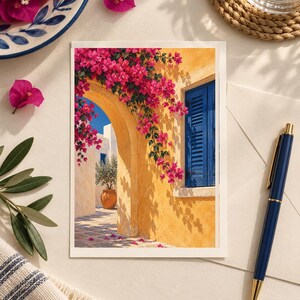May include: A rectangular greeting card featuring a vibrant illustration of a yellow Mediterranean building with a blue shuttered window and an arched doorway draped in bright pink bougainvillea flowers, with a potted olive tree visible.