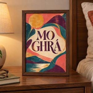 May include: A rectangular framed art print featuring a stylized landscape with a yellow sun, rolling hills in shades of teal, purple, and pink, and a reflective body of water. The text MO GHR&Aacute; is printed in large, dark purple serif lettering.