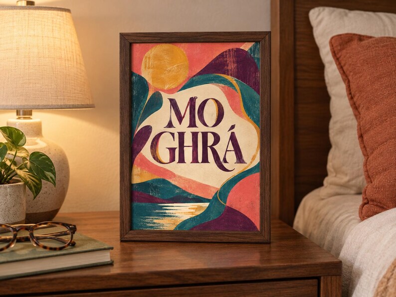 May include: A rectangular framed art print featuring a stylized landscape with a yellow sun, rolling hills in shades of teal, purple, and pink, and a reflective body of water. The text MO GHR&Aacute; is printed in large, dark purple serif lettering.