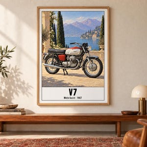 May include: A framed wall art print featuring a vintage Moto Guzzi V7 motorcycle parked on a stone terrace overlooking a lake and mountains. The text V7 and Moto Guzzi 1967 is printed in black at the bottom of the white border of the poster.