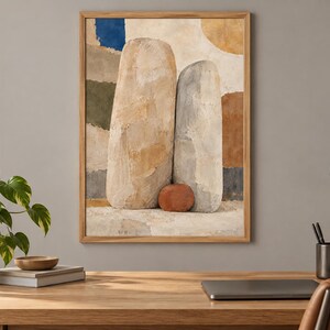 May include: A framed wall art print featuring an abstract composition of two large, textured, light-colored vertical stone-like shapes and one small, round, reddish-brown stone at their base, set against a background of muted blue, green, and tan blocks.