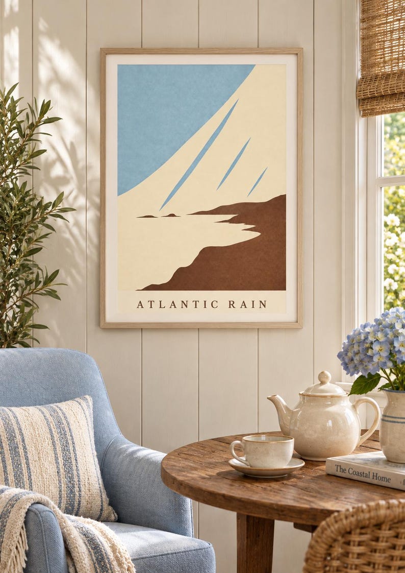 May include: A framed wall art print titled ATLANTIC RAIN featuring a minimalist landscape illustration with a light blue sky, cream-colored diagonal streaks, and a dark brown coastline. The artwork is displayed in a light wood frame.